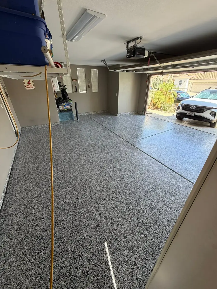 Gray flake epoxy garage floor with a car in the driveway, finished by Epoxy Dept